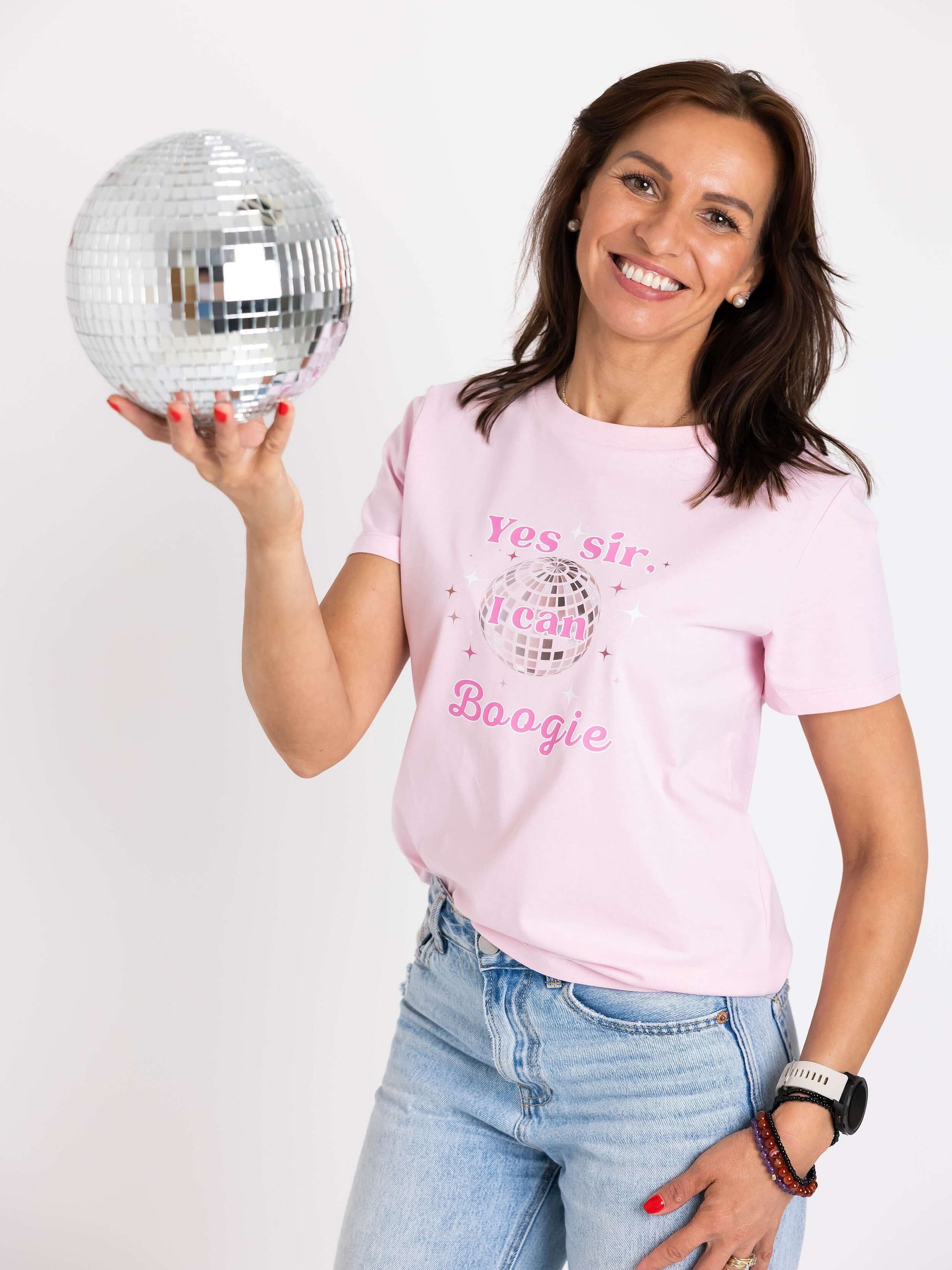 Woman wearing Pink round neck short sleeve womens top holding a disco ball. Yes Sir I Can Boogie slogan t shirt design with mirror ball. Organic Cotton Ladies Disco T-shirt