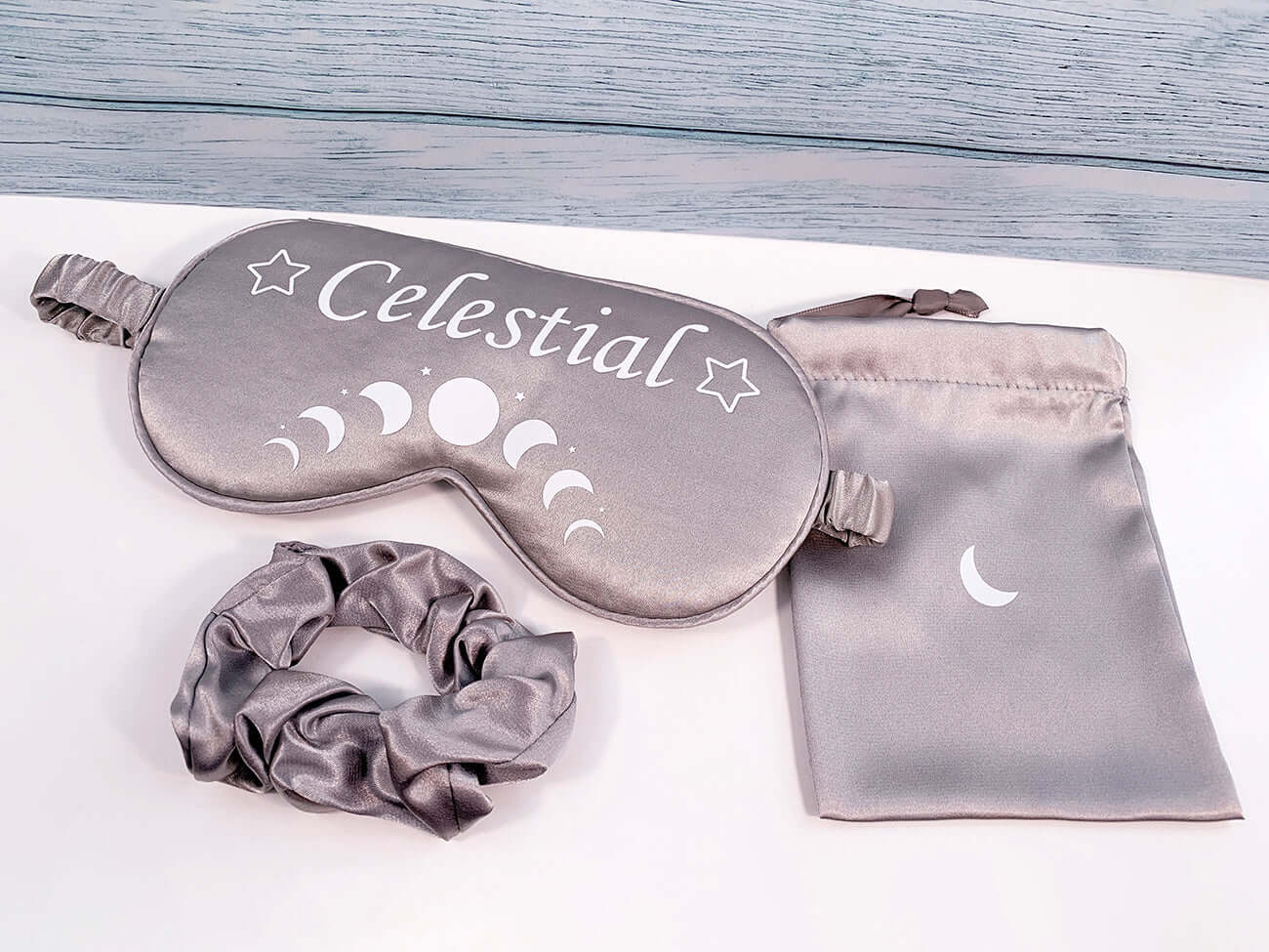 Gift set contents Silver Grey satin sleep mask with moon cycles in white and wording Celestial with star putline either side. Matching silver satin  hair scrunchie and satin small storage bag with crescent moon design