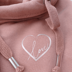 Close up of Ladies Cowl Neck Hoodie - Dusky Pink hoodie with rose gold metallic love heart motif. and words Love in script font inside heart. Cross neck hood and metallic eyelet for thick cotton drawstrings with metal toggle