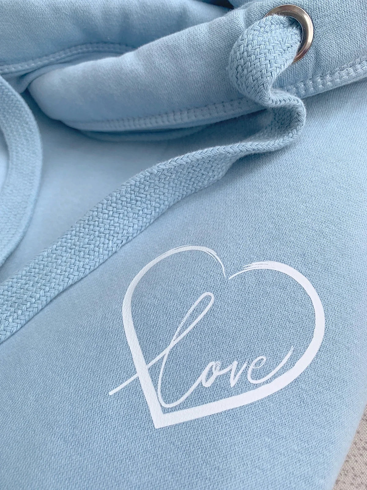 Light blue hoodie with a white heart-shaped 'love' design on the chest.