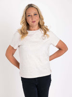 Woman wearing a off white ladies t-shirt with a small coffee cup logo motif  on the chest. Womens Cotton T shirt for Summer. Coffee Club Graphic T-shirt
