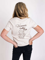 Woman wearing a off white t-shirt with mocha brown ' Vienna Coffee Club ' design on the back. Womens Graphic T-shirt for summer