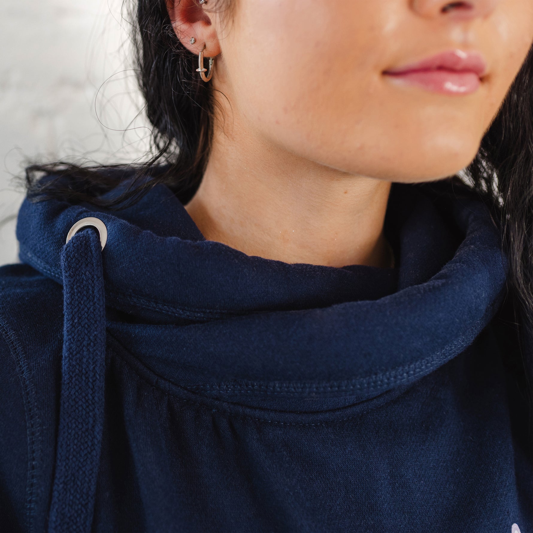 Close up of ladies Navy blue hoodie with cross cowl neck. Unisex oversized hoodie. Metal eyelets to drawstrings within hood.