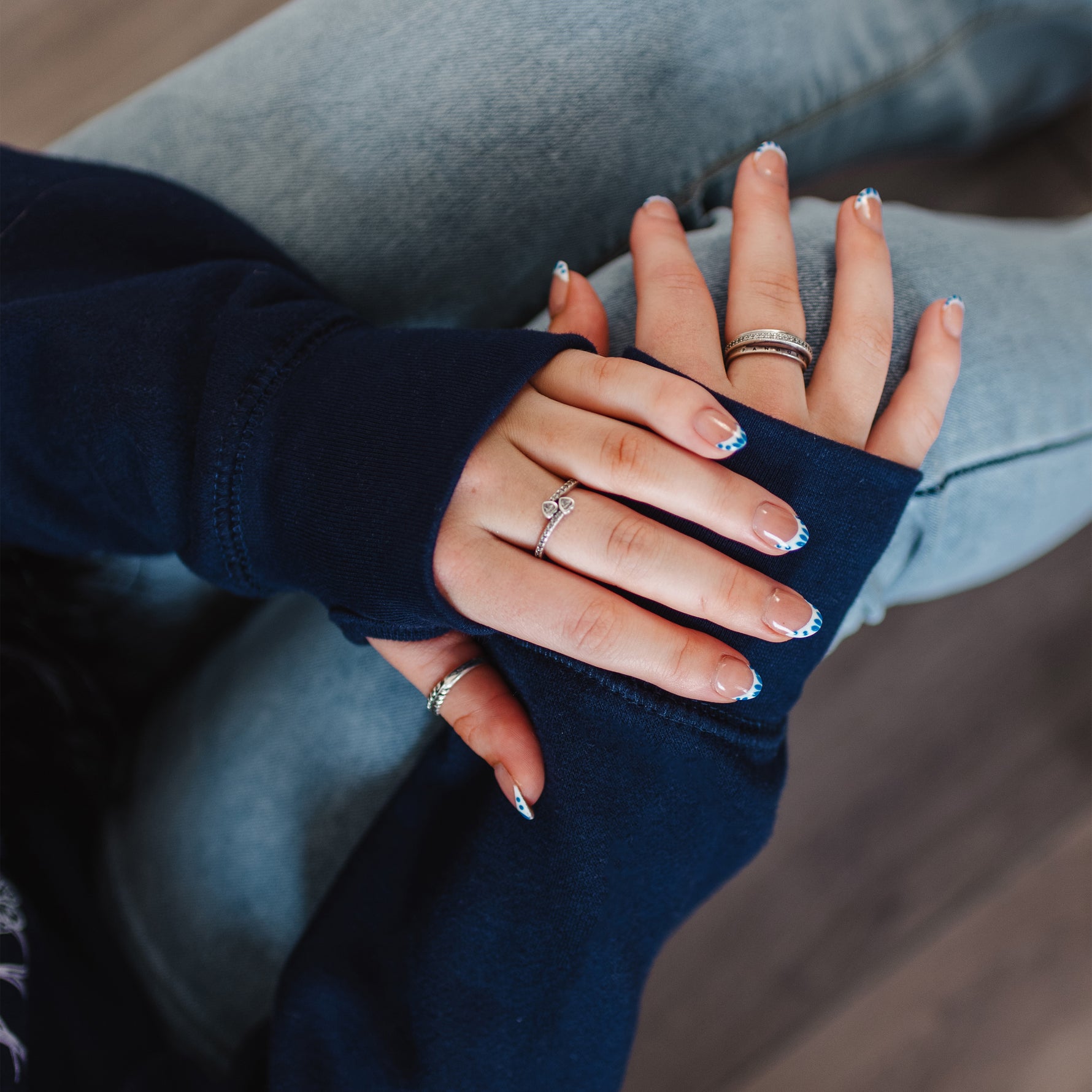 Close up of Womens Navy blue hoodie with cross cowl neck. Positive slogan and light grey butteflies design.  Unisex oversized hoodie. Long sleeves and thumb loops to cuffs 