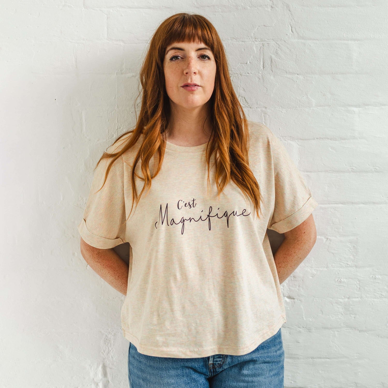 Ladies T-Shirt with dolman sleeve, rib neck collar and sleeve cuff fold. Rainbow Heather - light beige/cream base colour with multicolour flecks. Oversized women’s t-shirt with a short sleeves, inspired by the 1990s oversize trend.. Black slogan script font design reads French phrase C'est Magnifique