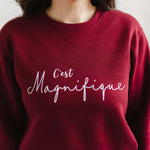 Ladies trendy sweatshirt with slogan french wording C'est Magnifique. Womens Burgundy red sweatshirt top with relaxed fit crew neck and long sleeves. Slogan is in white script font. 