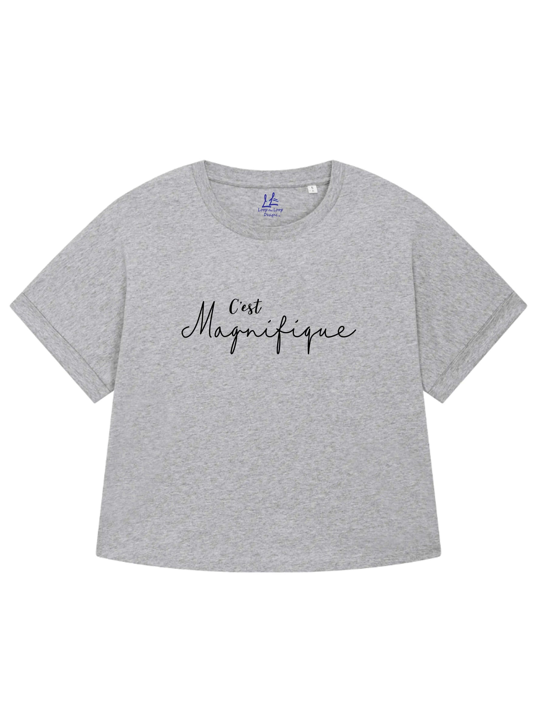 Light heather grey ladies T-Shirt with dolman sleeve, rib neck collar and sleeve cuff fold. Rainbow Heather - light beige/cream base colour with multicolour flecks. Oversized women’s t-shirt with a short sleeves, inspired by the 1990s oversize trend.. Black slogan script font design reads French phrase C'est Magnifique