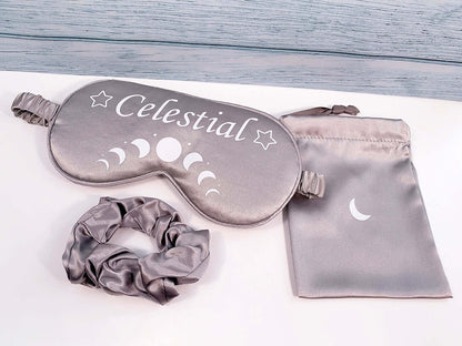 Gift set contents Silver Grey satin sleep mask with moon cycles in white and wording Celestial with star putline either side. Matching silver satin  hair scrunchie and satin small storage bag with crescent moon design 