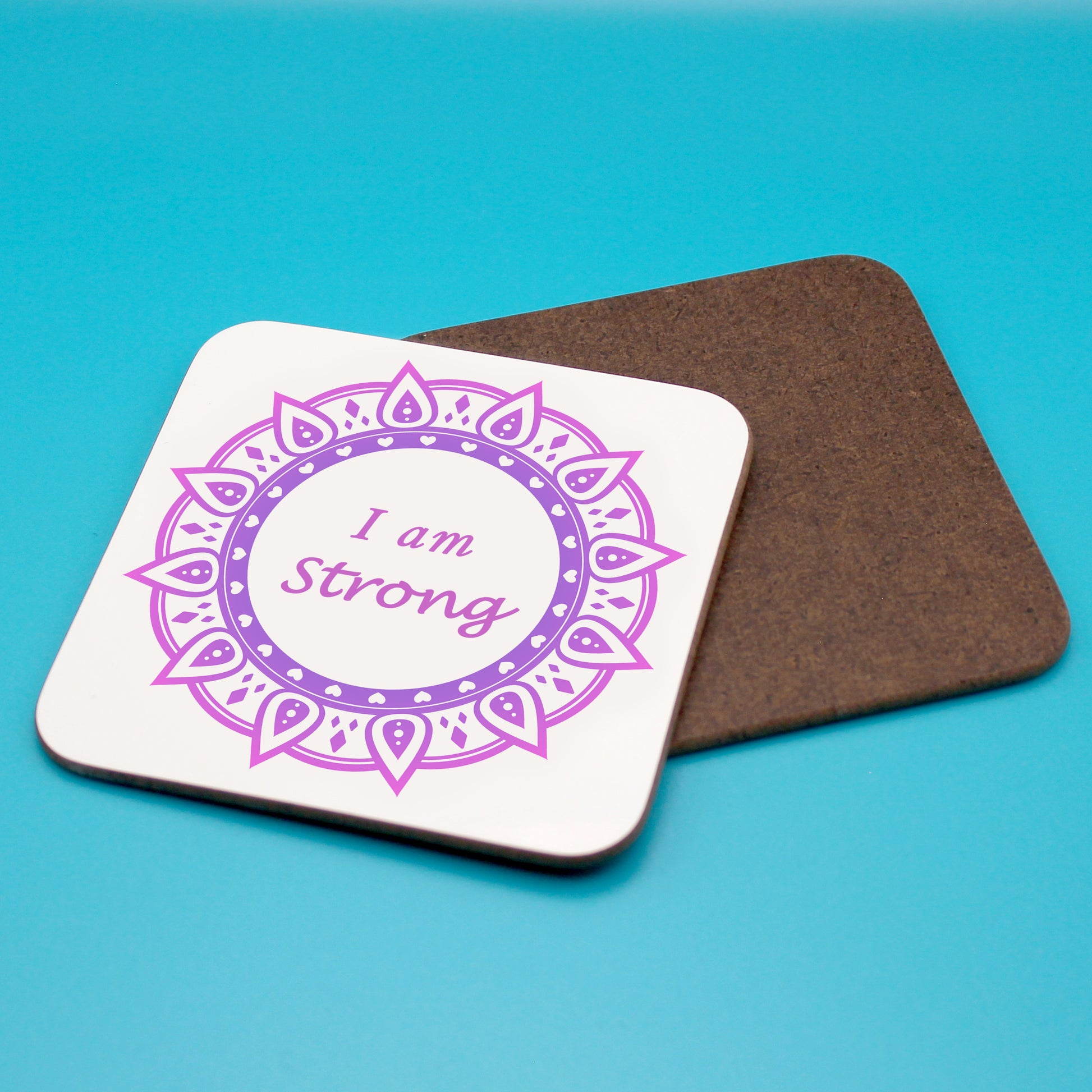White positive affirmation coaster with two-tone purple mandala design. Daily affirmation reads I am Strong. Coaster underneath shows wood backing