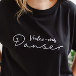 Close up of womens oversized black t shirt with short loose sleeves with roll cuffs. The ladies tshirt has the words Voulez Vous Danser in white