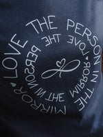 Women's Love the Person in the Mirror relaxed fit ink grey graphic t shirt with short sleeves. Infinity symbol and heart design and circular wording in white Love the Person in the Mirror in reverse on inner circle and right way round on outer circle so that wording.