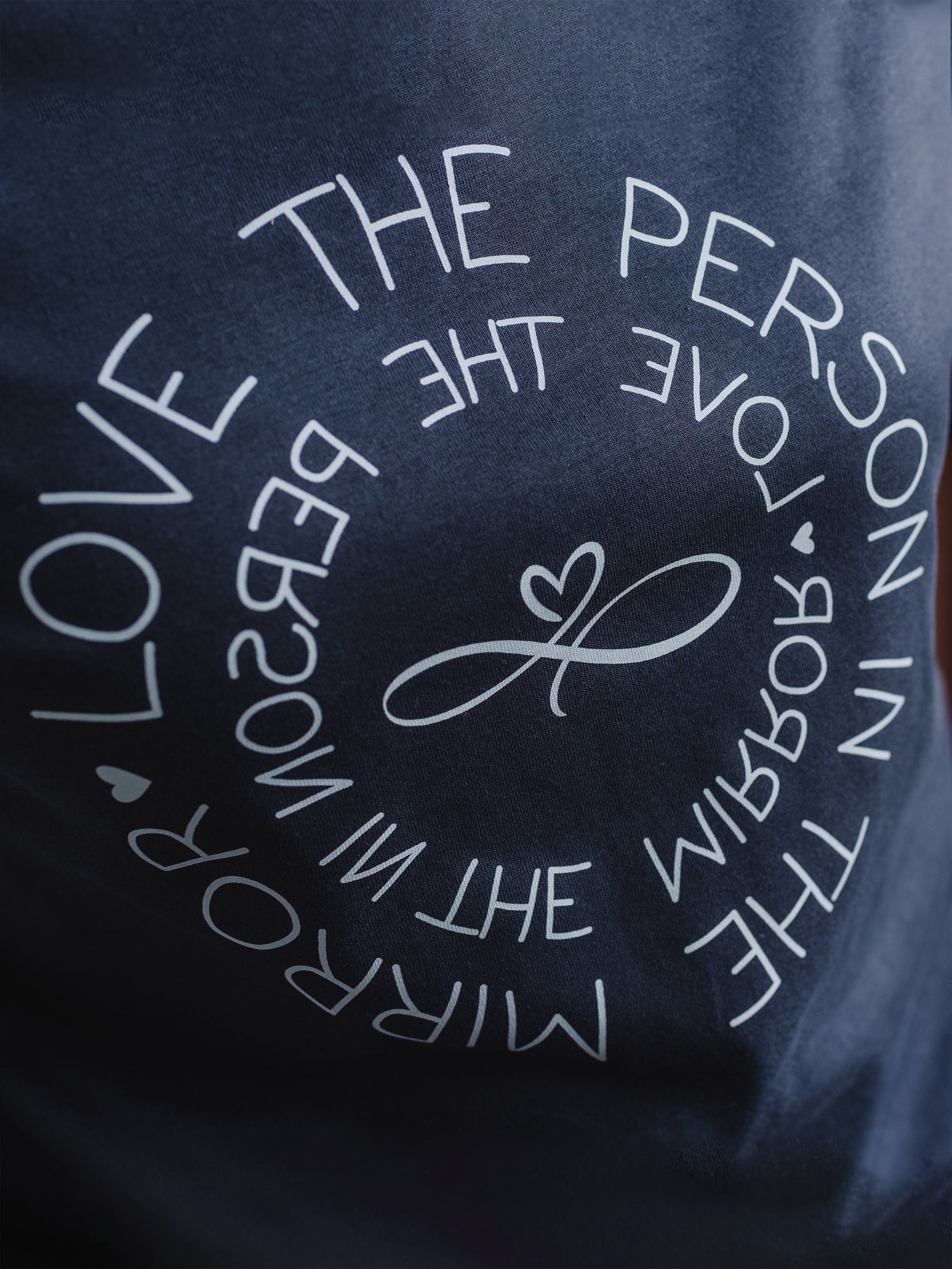 Women's Love the Person in the Mirror relaxed fit ink grey graphic t shirt with short sleeves. Infinity symbol and heart design and circular wording in white Love the Person in the Mirror in reverse on inner circle and right way round on outer circle so that wording.