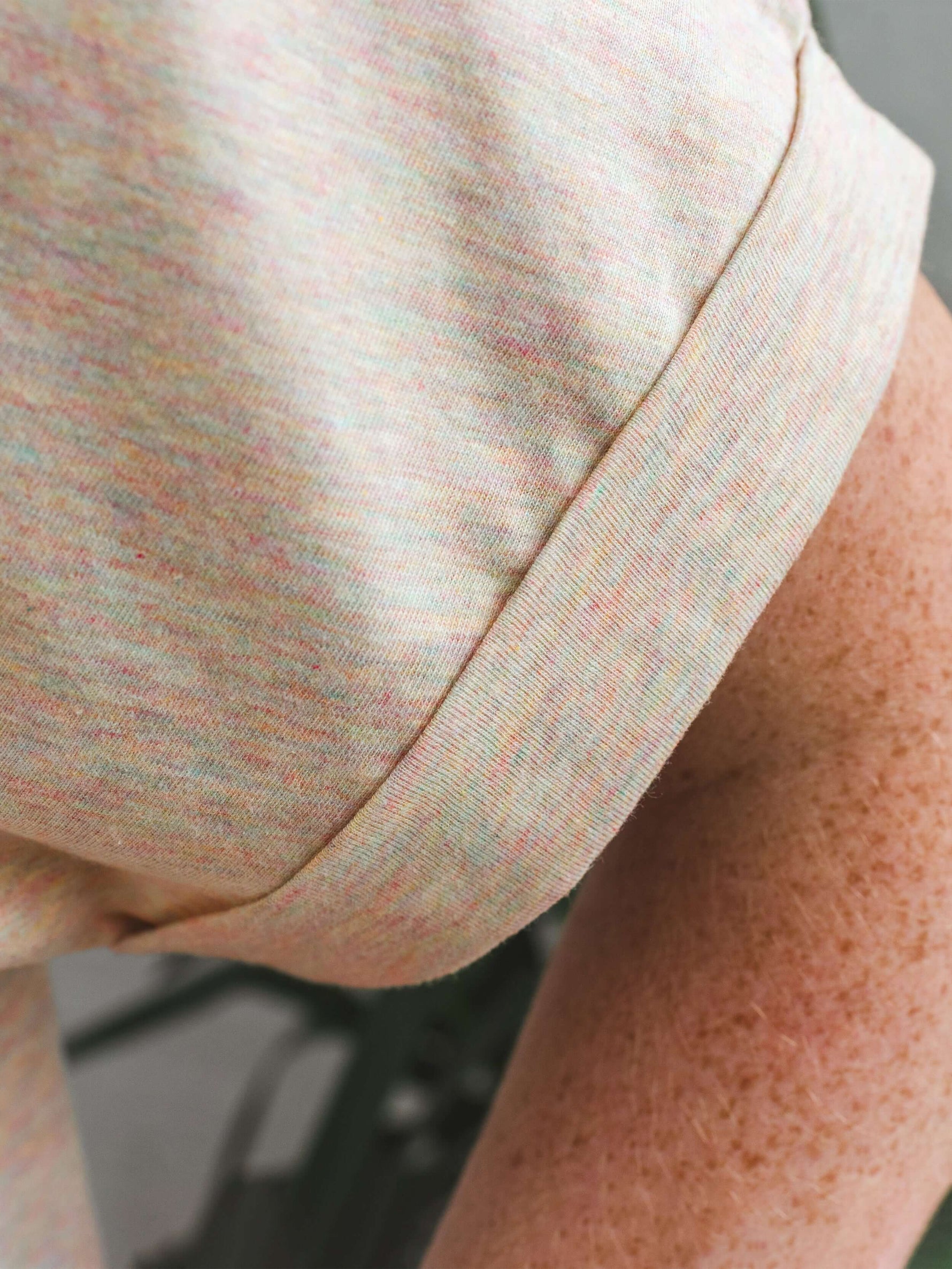 Close up image of ladies t-shirt dolman loose sleeves. Ladies top with sleeve cuff folded with bartacks. Rainbow heather colour Tee