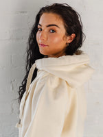 Ladies Cowl Neck Hoodie - Side view of Cotton Vanilla cream hoodie with hood, and long sleeves. Cross neck sweatshirt with hood and thick fabric drawstrings with metal toggle