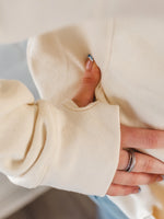 Close up of vanilla cream ladies hoodie sleeve detail. Long sleeves with thumb holes to sleeve cuff. 