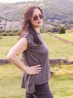 Woman outside wearing sunglasses. Summer Festival Women's Band Tee. Ladies T shirt Grey cotton cap sleeve t shirt with lightning bolt design and slogan I'm with the Band.  Side view shows lower hem design at the back. 