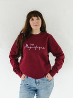 Caucasian woman with long brown hair wearing blue acid wash jeans and a burgundy red relaxed fit sweatshirt jumper with crew round neck and long sleeves with cuffs. 