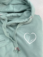 Close up photo of relaxed fit mid green hoodie with thumb holes to long sleeve arm cuffs