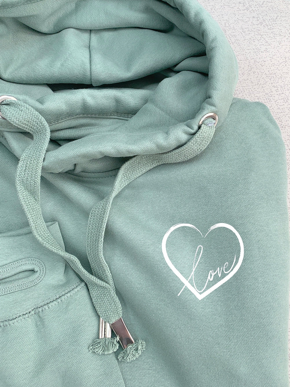 Close up photo of relaxed fit mid green hoodie with thumb holes to long sleeve arm cuffs