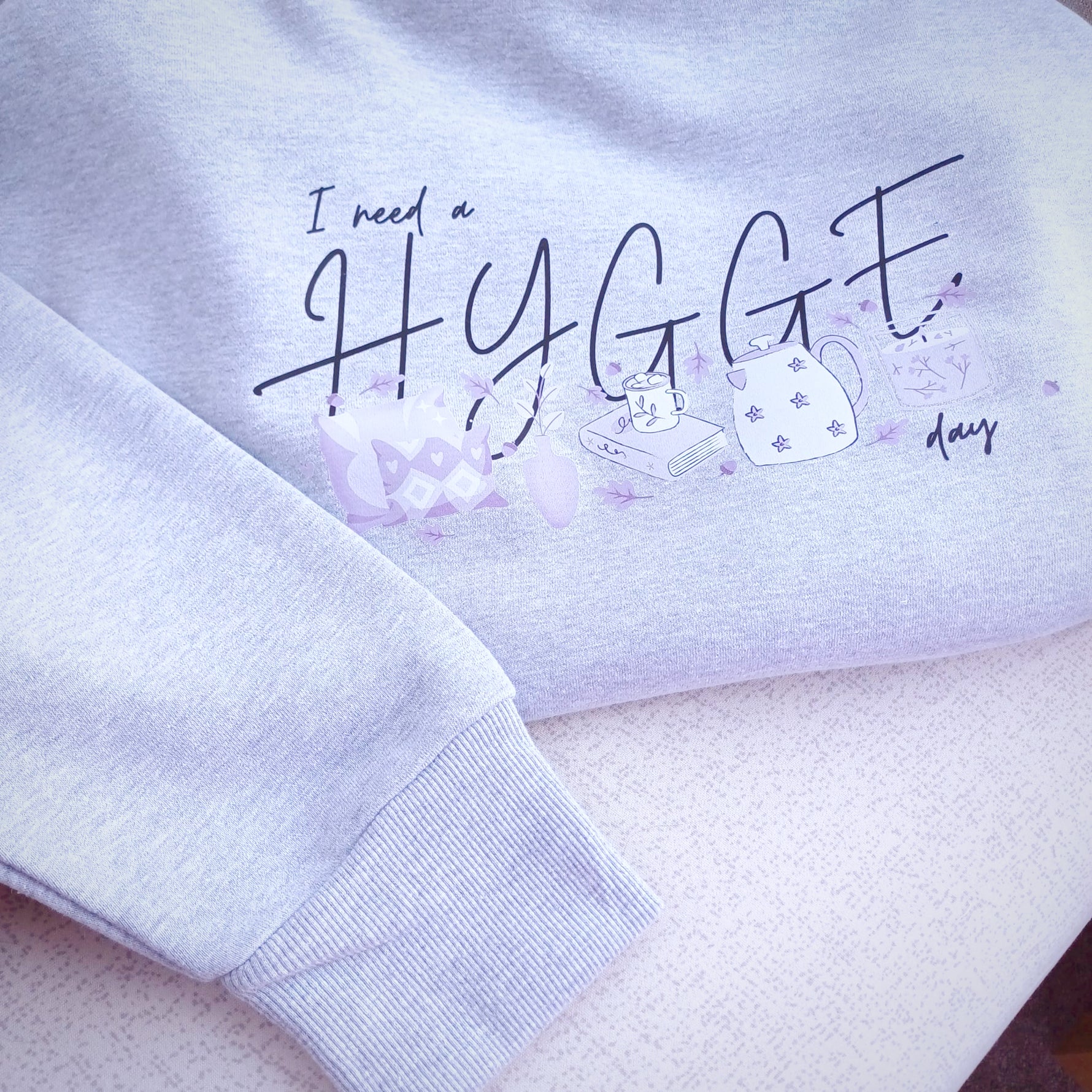 Ladies oversized heavy hoodie with long sleeves and hood without drawstrings. Close up of slogan designs I need a Hygge day with hygge home inspired items for hygge lifestyle