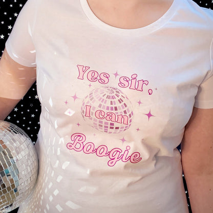 Woman holding a silver disco ball, wears leggings and white round neck fitted tshirt. 70s disco music inspired womens white graphic tshirt with purple tint mirrorball and sparkles surround. Slogan text reads Yes sir I can Boogie in two tone pink font