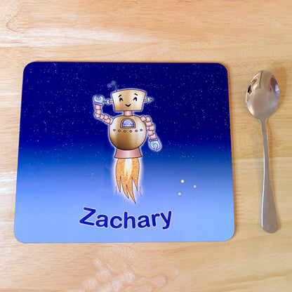 Light and bright blue star sky kids placemat set. Robot smiling with jets flying into space. Personalised with girl's name at the bottom of custom child's dinner mat. Kids spoon next to mat