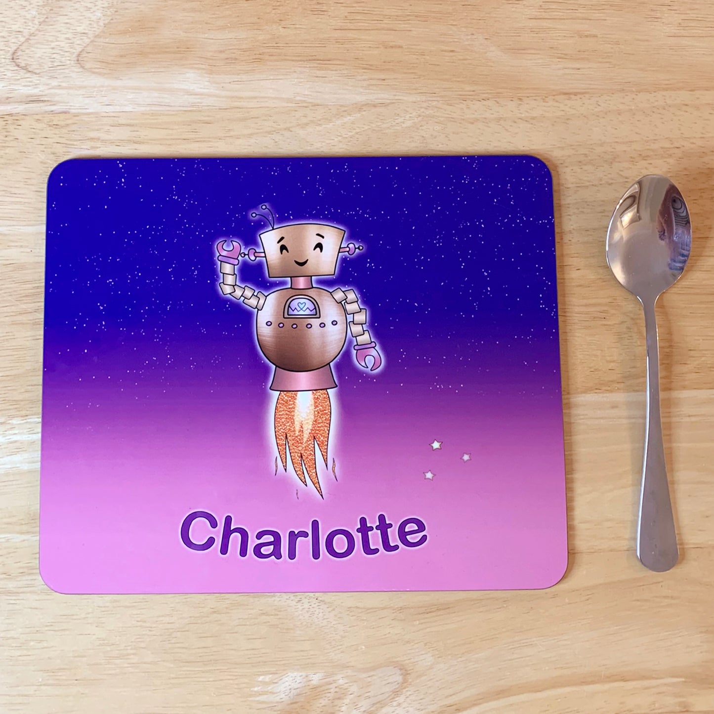 Pink and purple star sky kids placemat set. Robot smiling with jets flying into space. Personalised with girl's name at the bottom of custom child's dinner mat Kids spoon next to mat