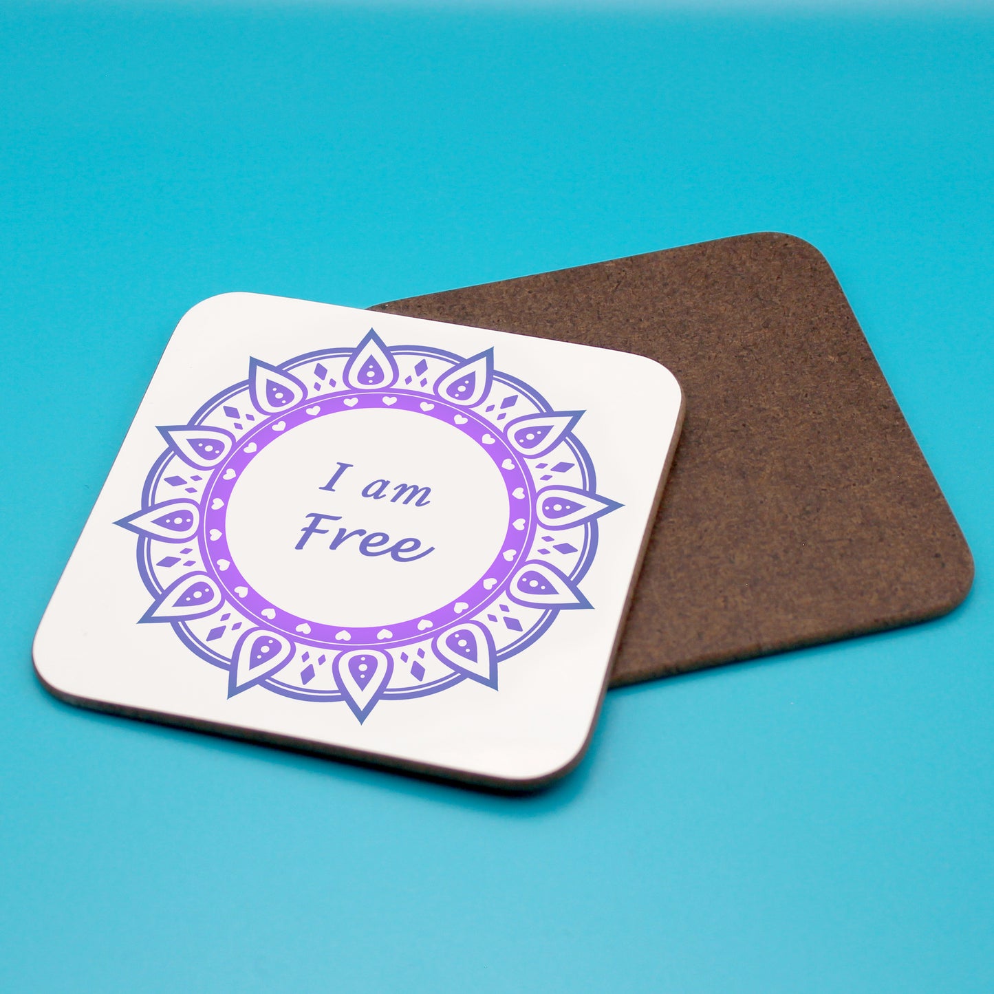 White personal affirmation coaster with tow-tone purple mandala design. Daily affirmation reads I am Free. Coaster underneath shows wood backing