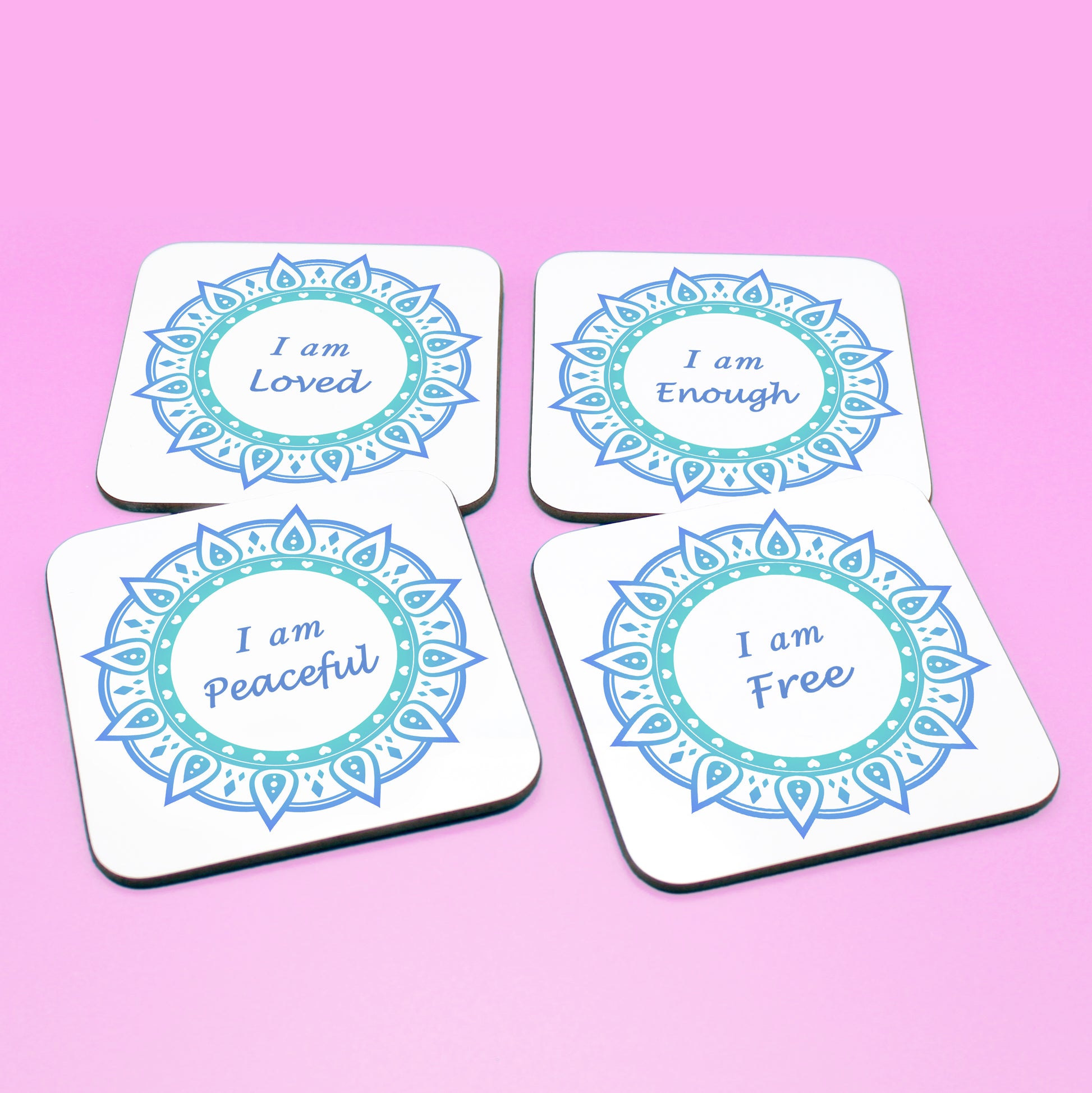 Wellbeing gift. Four square wooden backed personal affirmations coaster set. Theme is Letting Go in this set of four. Mandala design with daily affirmation wording inside the mandala.  Affirmations read I am Loved, I am Enough, I am Peaceful, I am Free (all coaster mandalas are a blue mandala),