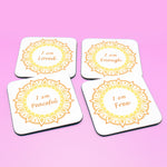 Wellbeing gift. Four square wooden backed personal affirmations coaster set. Theme is Letting Go in this set of four. Mandala design with daily affirmation wording inside the mandala.  Affirmations read I am Loved, I am Enough, I am Peaceful, I am Free (all coaster mandalas are a yellow and orange mandala),