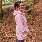 Longline ladies hoodie.  Woman wears aby pink womens hoodie Love heart cross cowl neck casual fashion hoodie. Cotton Polyester blend relaxed fit unisex oversized style hoodie design has love heart. Whitert to upper left of the chest with word Love in white script font nestled within the heart