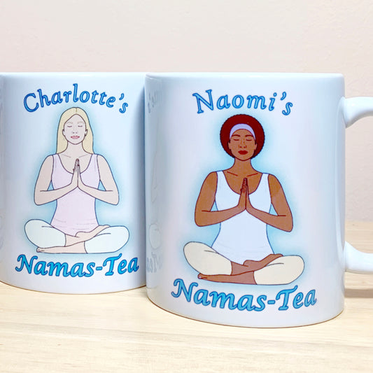 2 white coffee cups with different customisations. Personalised gift for her, womans yoga mug. Both white 11oz coffee mugs are personalised. Name at the top in blue font and Namas-tea wording at the bottom in same font. Customised by ethnicity, outfit and hair, this shows a woman in a seated yoga position with hands to heart centre and eyes closed. 