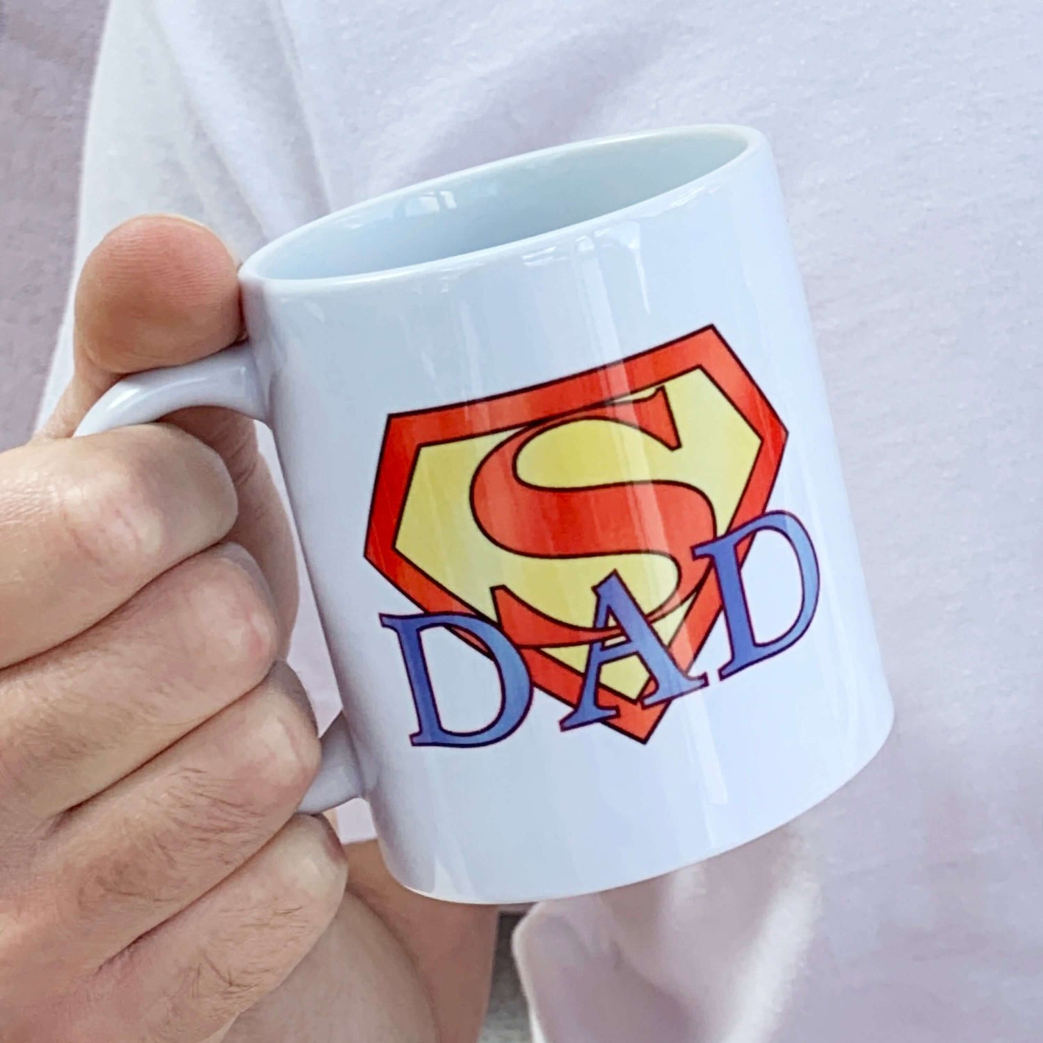 Personalised gift for Dad - Birthday or Father's Day Gift ideas - Personalised present with message on reverse side of mug not shown in this image. SuperDad themed design. White ceramic coffee mug with red and yellow Superman Logo design and blue wording 