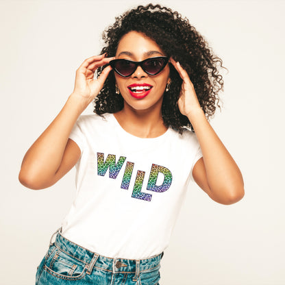 Womens Fashion Top. White organic cotton womens tshirt with rainbow animal print slogan on tee reads WILD. Woman wearing sunglasses smiling