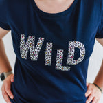 Cool Womens Leopard Print Fashion Top. Navy blue t-shirt with round neck and short sleeves. Organic cotton ladies t shirt with multi colour spots animal print slogan on Tee reads WILD